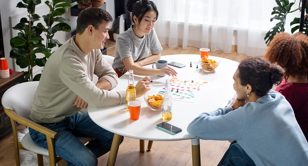 Een groep vrienden speelt thuis aan tafel een bordspel